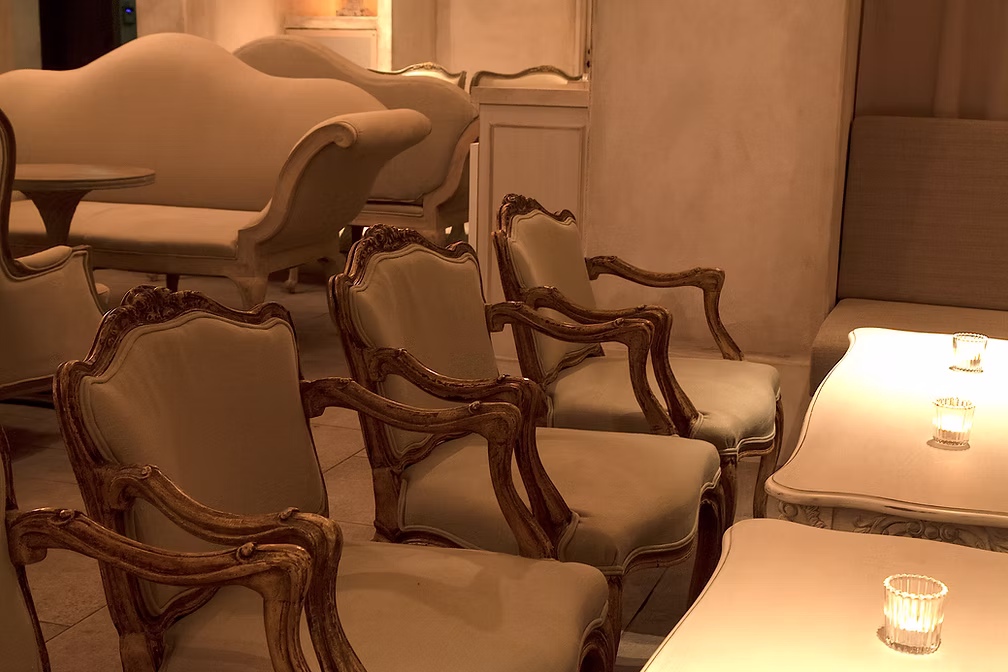 Upholstered chairs and low tables lit by candles